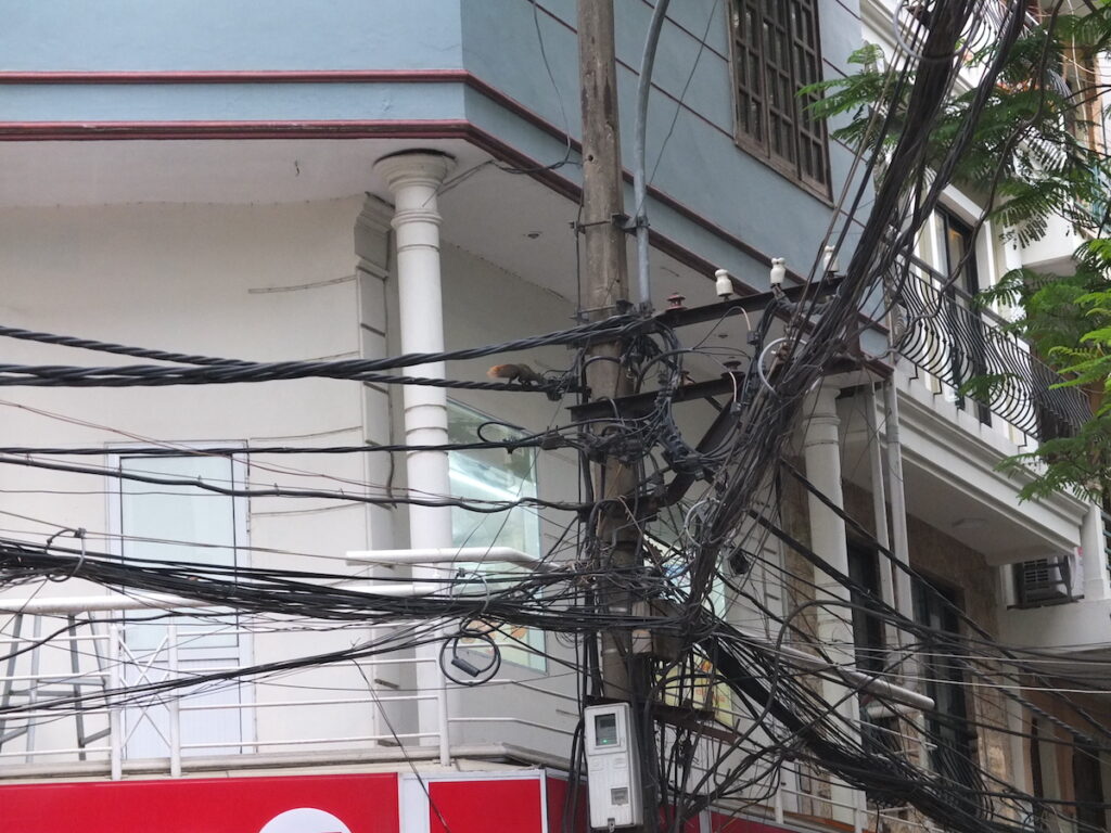 Photo of electrical chords tangled together near the side of a building