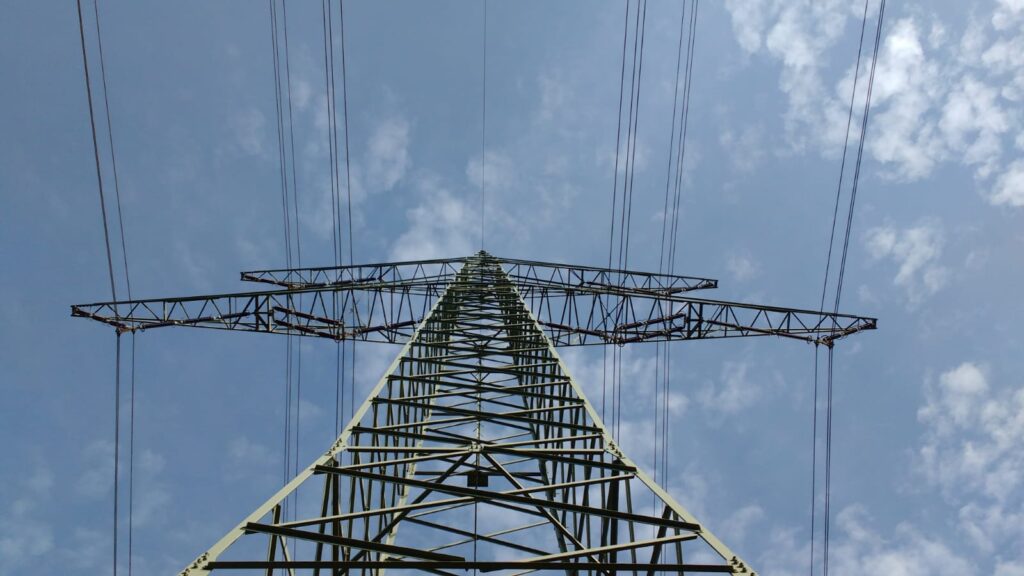 Photo of power lines running through transmission tower, taken looking up from below.