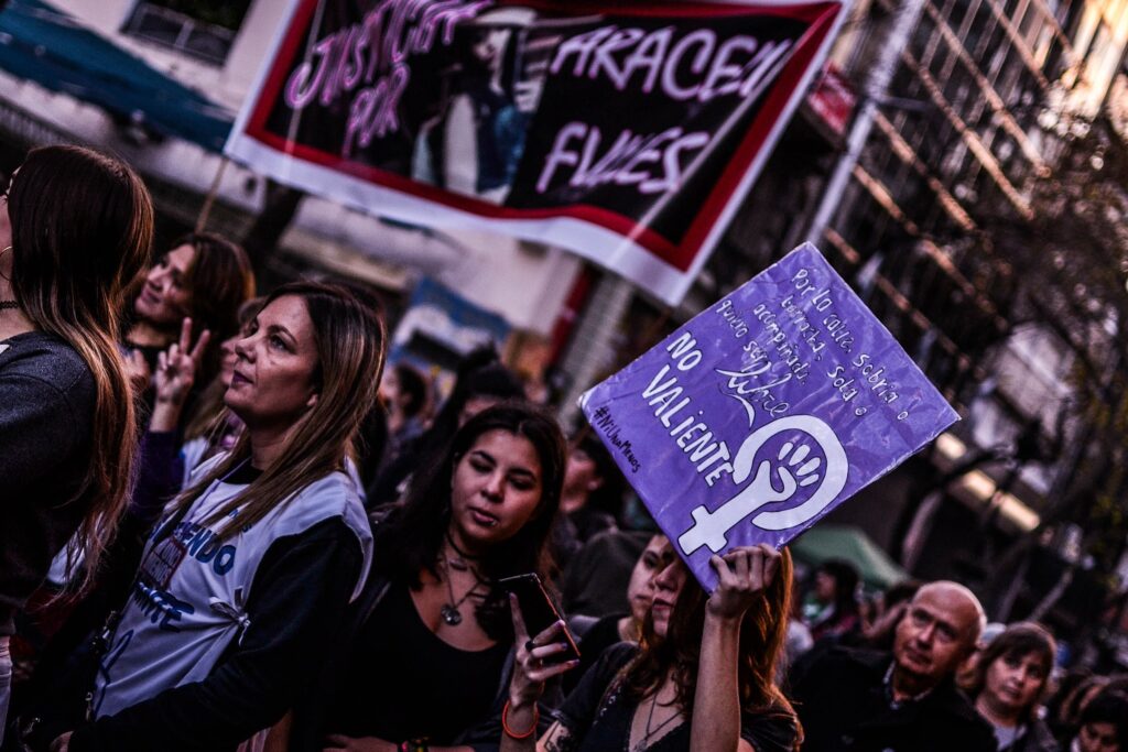 Women march down a street holding protests signs. 