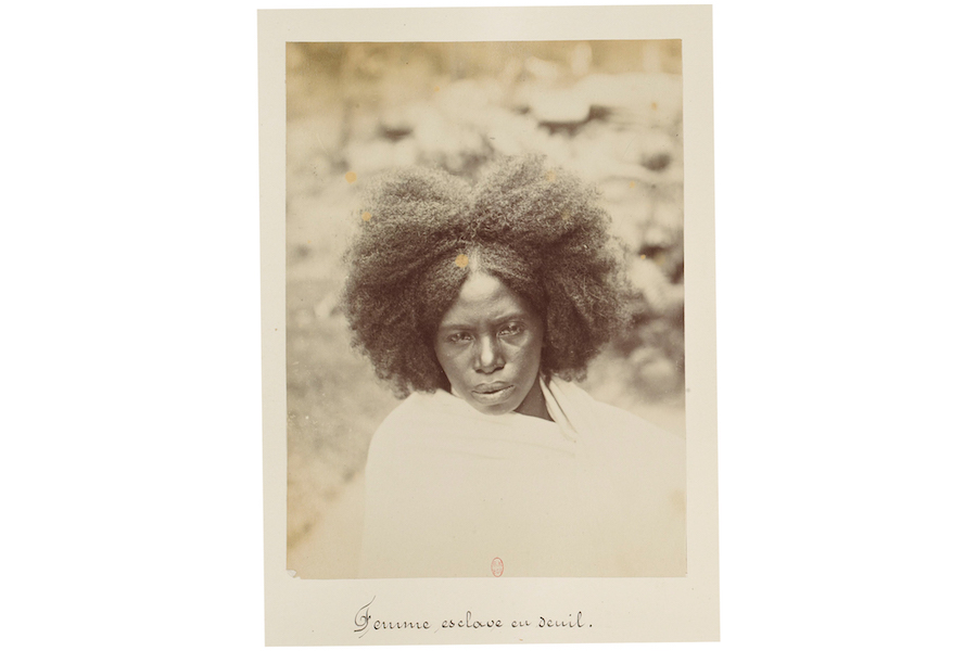 Historic sepia photograph of a Black woman wearing white looking directly into the camera.